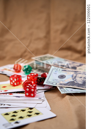 Poker deck spread out on a table with a pile of different dice and dollars. 122006601