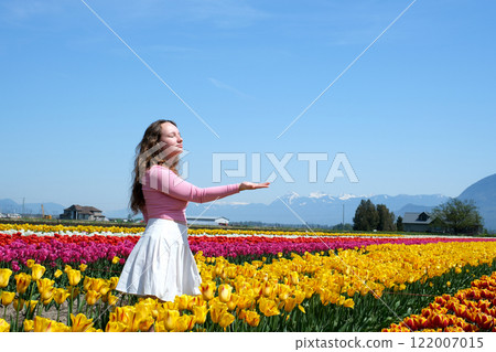 Young woman tourist in pink dress and straw hat standing in blooming tulip field. Spring time Young woman tourist in pink dress and straw hat standing in blooming tulip field. Spring time 122007015