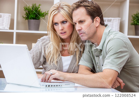 Worried Man and Woman Couple Using a Laptop Computer at Home Worried Man and Woman Couple Using a Laptop Computer at Home 122008524