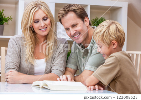Happy Family Parents Teaching Child to Read a Book At Home Happy Family Parents Teaching Child to Read a Book At Home 122008525