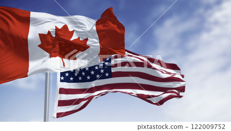 Canada and american national flags waving in the wind on a clear day Canada and american national flags waving in the wind on a clear day 122009752