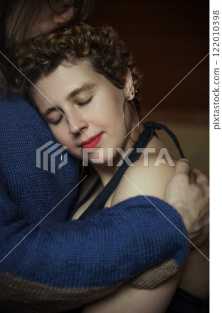 Embrace shared in a cozy indoor setting during an intimate moment between partners 122010398