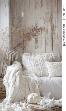rustic interior with soft knitted pillows and blankets in white tones, dried plants, and minimal autumn decor 122010568