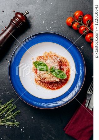 Italian lasagna served on a blue plate with basil garnish and parmesan, perfect for a gourmet feast 122010643
