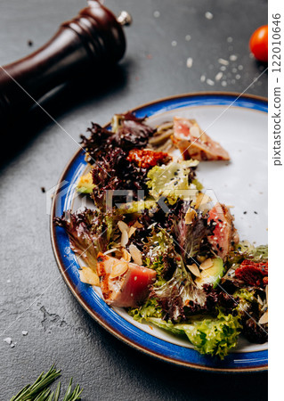 Fresh gourmet salad with seared tuna, avocado, and sundried tomatoes on a vibrant plate 122010646