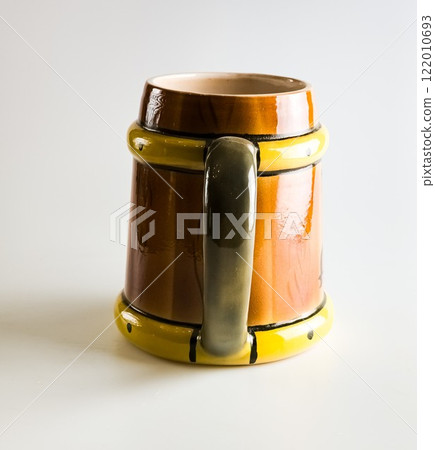Empty clay mug on a white background. Brown beer mug in the shape of a barrel. 122010693