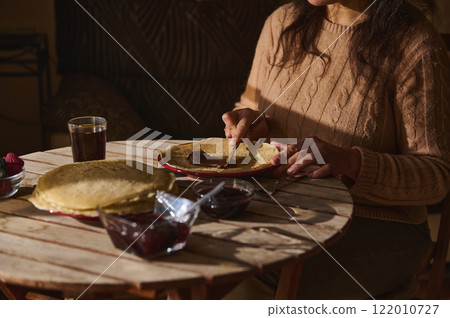 Woman Preparing Pancakes with Spreads During a Daytime Meal 122010727