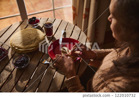 Woman Enjoying Pancakes with Berries and Jam in Morning Light Woman Enjoying Pancakes with Berries and Jam in Morning Light 122010732
