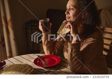 Woman enjoying breakfast with pancakes and warm light in the morning Woman enjoying breakfast with pancakes and warm light in the morning 122010735