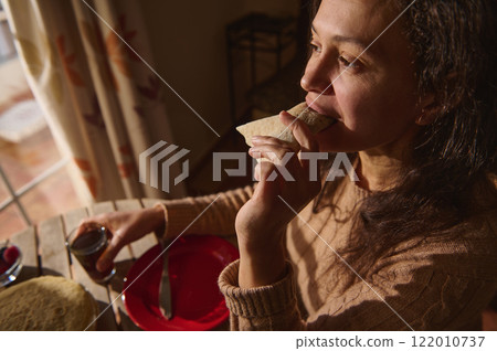 Woman enjoying a crepe with drink at a cozy breakfast setting Woman enjoying a crepe with drink at a cozy breakfast setting 122010737