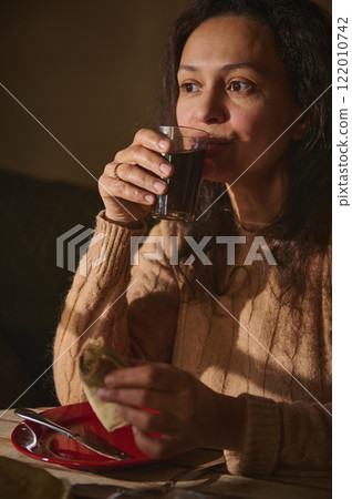 Woman enjoying a pancake and drink in a cozy setting 122010742