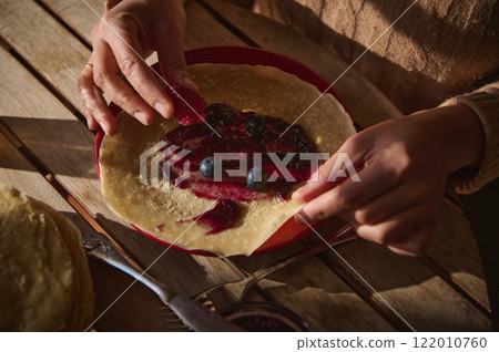 Hands Preparing a Crepe with Jelly and Fresh Berries on Wooden Table Hands Preparing a Crepe with Jelly and Fresh Berries on Wooden Table 122010760