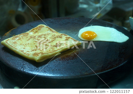 Flatbread cooking beside a fried egg in a busy kitchen Flatbread cooking beside a fried egg in a busy kitchen 122011157