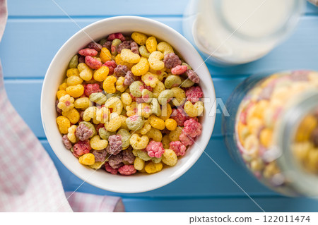 Colorful breakfast cereals in the shape of various fruit in bowl on blue table. Top view. 122011474