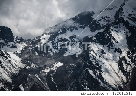 Majestic snowy mountain peaks under dramatic cloudy skies in Nepal. Concept of rugged wilderness, Himalayan beauty, and alpine adventure. Majestic snowy mountain peaks under dramatic cloudy skies in Nepal. Concept of rugged wilderness, Himalayan beauty, and alpine adventure. 122011512