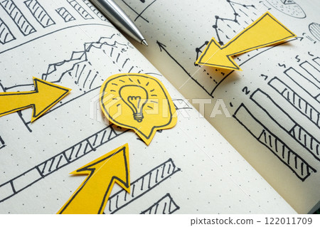 Arrows pointing to light bulb and financial graphs. Business strategy and innovative solutions. 122011709