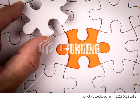 FUNDING Concept. White puzzle pieces and text on an orange background 122012142
