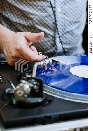 DJ spinning blue vinyl record on turntable, creating retro music vibes at an event 122012155