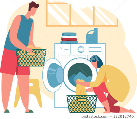Young man carrying laundry basket and woman loading clothes into washing machine while kneeling, performing household chores together in the laundry room 122012740