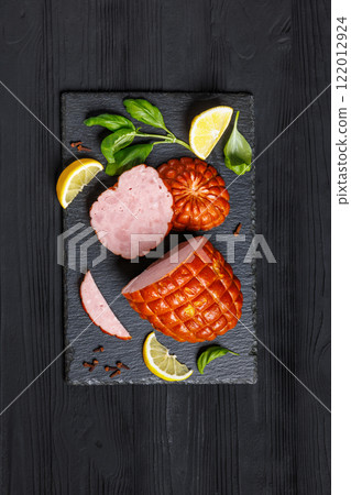boneless smoked ham on black slate board, top view boneless smoked ham on black slate board, top view 122012924