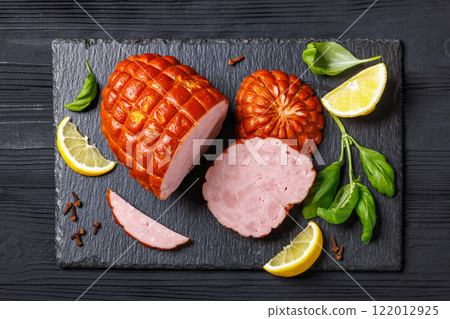 boneless smoked ham on black slate board, top view boneless smoked ham on black slate board, top view 122012925