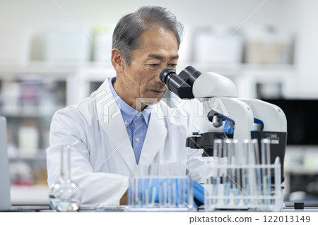 Senior man in a white coat working with a microscope. Image of experiment, research and development. 122013149