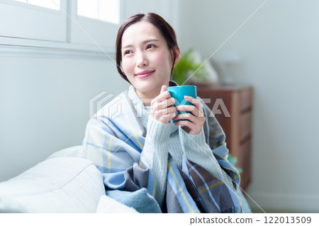 A woman warms herself by drinking a hot drink A woman warms herself by drinking a hot drink 122013509