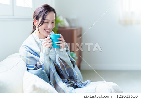 A woman warms herself by drinking a hot drink 122013510