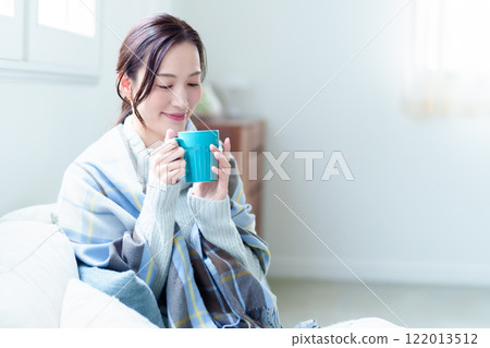 A woman warms herself by drinking a hot drink 122013512