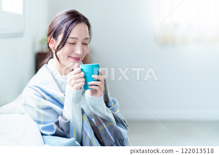 A woman warms herself by drinking a hot drink A woman warms herself by drinking a hot drink 122013518