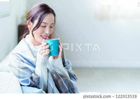 A woman warms herself by drinking a hot drink A woman warms herself by drinking a hot drink 122013519