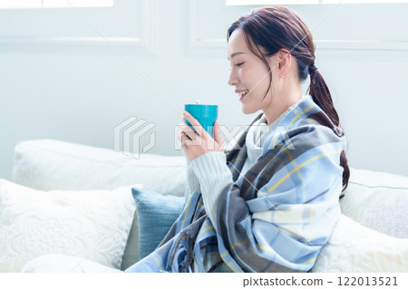 A woman warms herself by drinking a hot drink 122013521