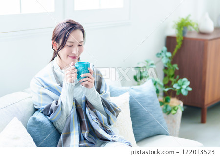 A woman warms herself by drinking a hot drink A woman warms herself by drinking a hot drink 122013523