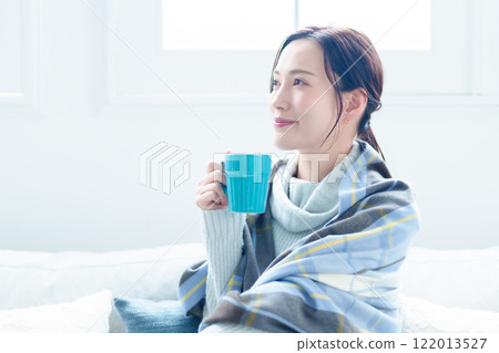 A woman warms herself by drinking a hot drink A woman warms herself by drinking a hot drink 122013527