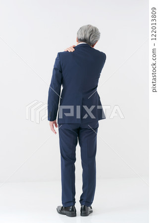 Senior man in a suit rubbing his shoulder Senior man in a suit rubbing his shoulder 122013809