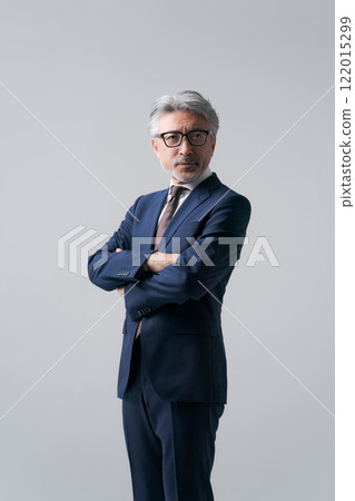 A businessman standing with his arms folded 122015299