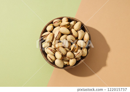 Pistachios in a plate, on a green background. 122015737