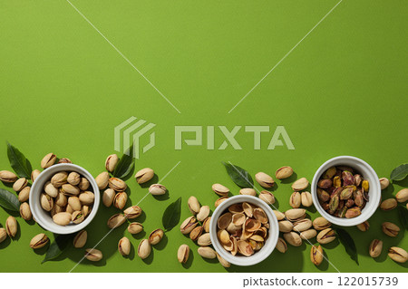 Pistachios in a plate, on a green background. 122015739