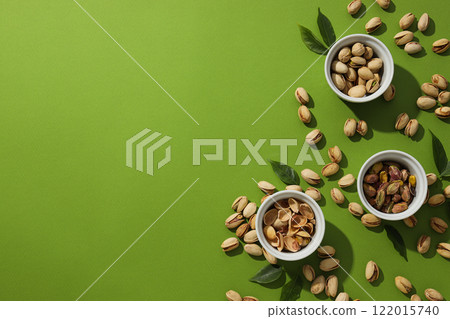 Pistachios in a plate, on a green background. 122015740