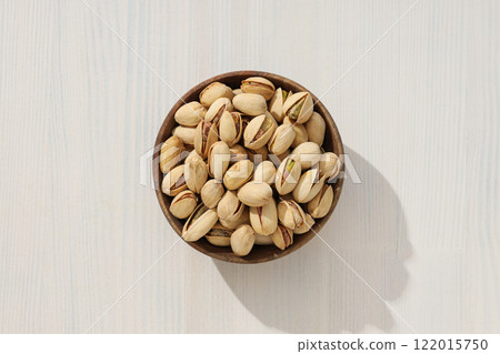 Pistachios in a wooden plate, on a light background. Pistachios in a wooden plate, on a light background. 122015750