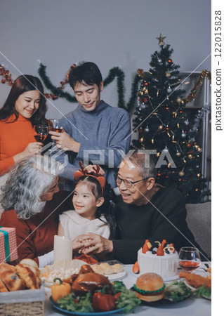 Multi-Generation Family Celebrate Christmas At Home Wearing Santa Hats And Antlers Opening Presents 122015828