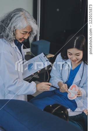 A team of doctors and nurses are working to treat a female patient in the patient's room. A team of doctors and nurses are working to treat a female patient in the patient's room. 122015873