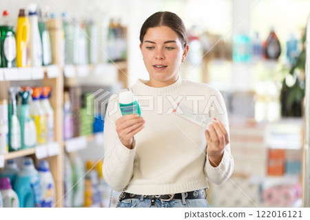 Girl housewife in household store examines goods, chooses oral hygiene products Girl housewife in household store examines goods, chooses oral hygiene products 122016121