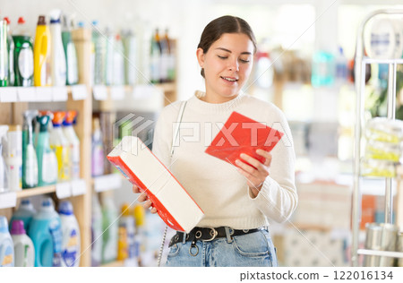 Young woman housewife in household store examines package, chooses paper napkin 122016134