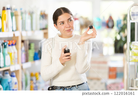 Young woman client sniffs fragrance of perfume, chooses scent spray with pleasant smell 122016161