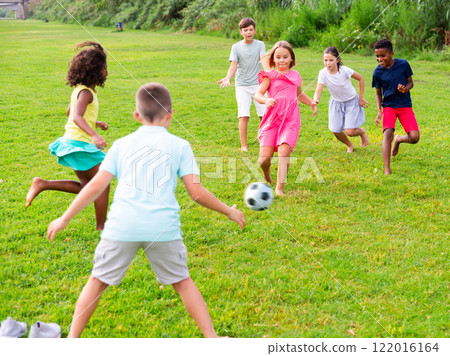 Kids running through grass and playing football 122016164