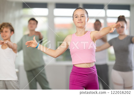 Teenage girl practicing ballet positions in dance studio 122016202