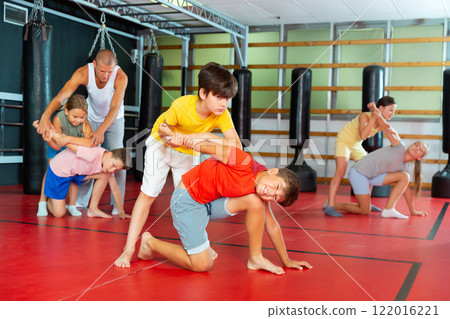 Boys and girls in gym exercising armlock move 122016221