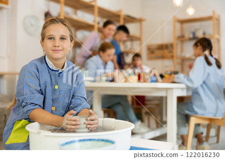 Girl working at a potter's wheel 122016230