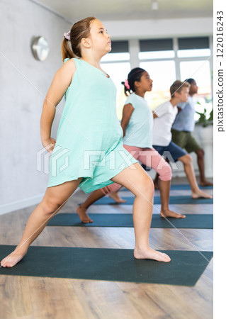 Girl stands in warrior pose, Virabhadrasana. Concept of active lifestyle of young generation 122016243